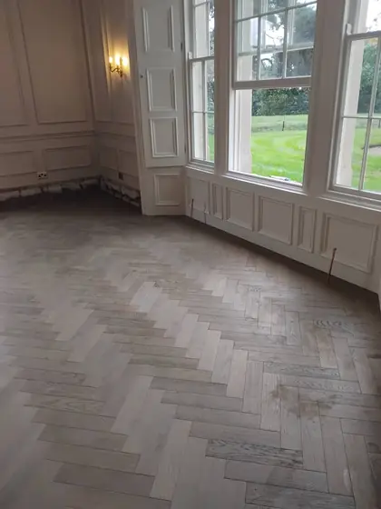 Grey engineered wood herringbone being fitted in a panelled period drawing room